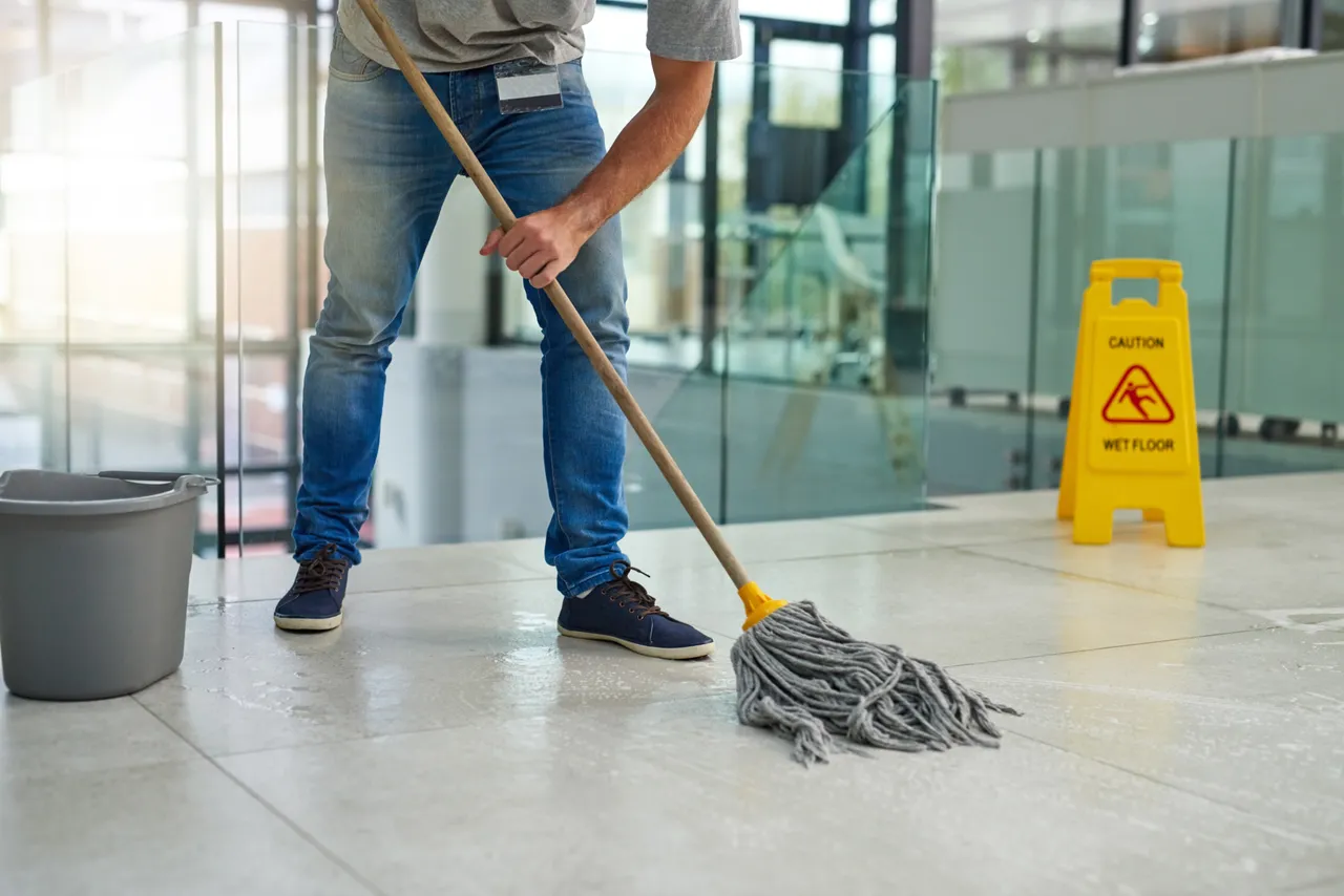 A cleaner mopping a commercial lobby floor