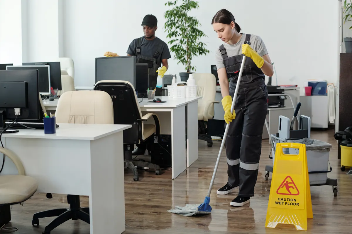 A team mopping floors and wiping desks in an office